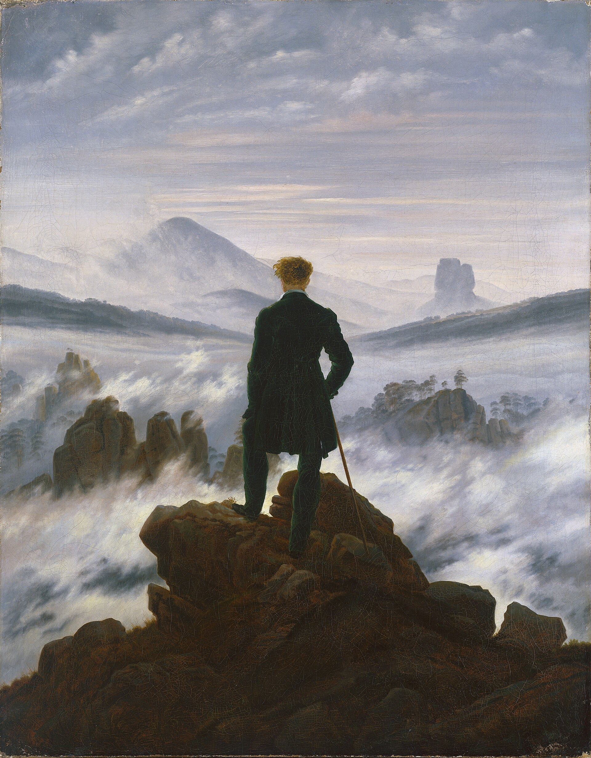 A lone figure looking out over a sea of fog from a rocky peak.
